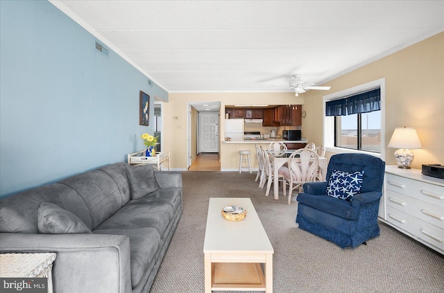 living room featuring crown molding, light colored carpet, visible vents, and ceiling fan