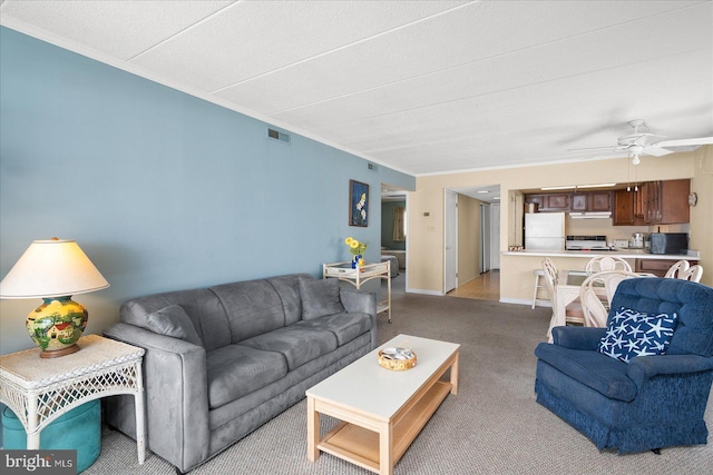 living area featuring light carpet, baseboards, visible vents, a ceiling fan, and crown molding