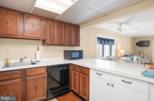 kitchen featuring black appliances, light countertops, a peninsula, and a sink