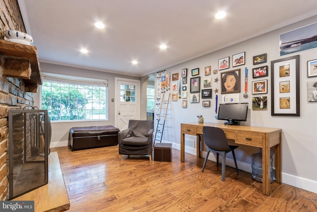 office area featuring light hardwood / wood-style floors, crown molding, and a fireplace