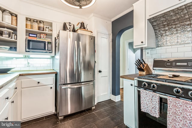 kitchen with appliances with stainless steel finishes, ornamental molding, white cabinetry, and tasteful backsplash