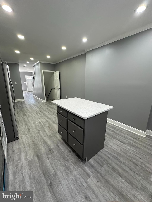 kitchen with stainless steel fridge, a kitchen island, crown molding, and light hardwood / wood-style flooring