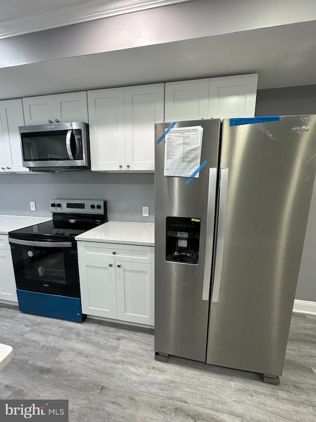 kitchen with light hardwood / wood-style flooring, appliances with stainless steel finishes, and white cabinetry