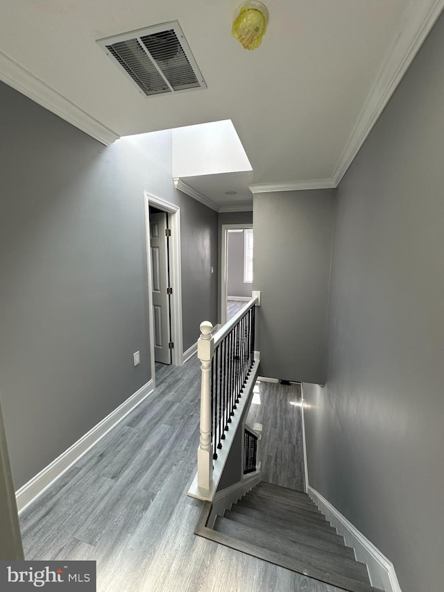 stairs with wood-type flooring and crown molding