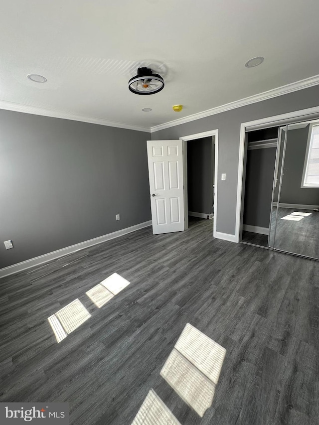 unfurnished bedroom with dark hardwood / wood-style floors, crown molding, and a closet