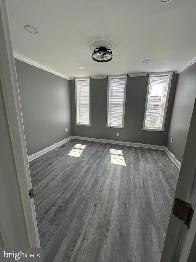 spare room with ornamental molding and dark hardwood / wood-style flooring