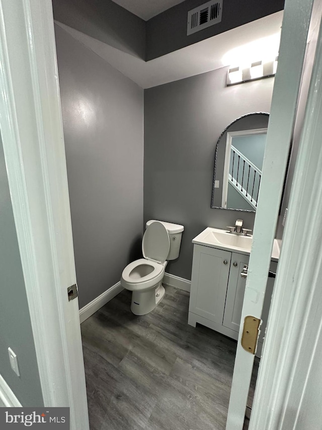 bathroom with vanity, toilet, and hardwood / wood-style flooring