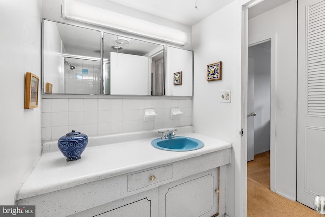 bathroom with a shower with door, vanity, and tasteful backsplash