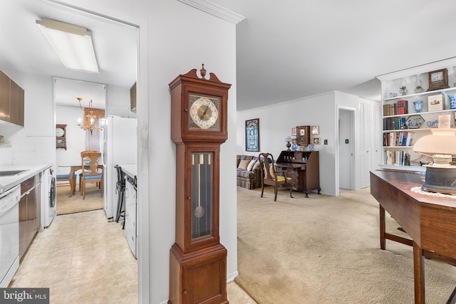 kitchen with washer / clothes dryer, white appliances, light colored carpet, and an inviting chandelier