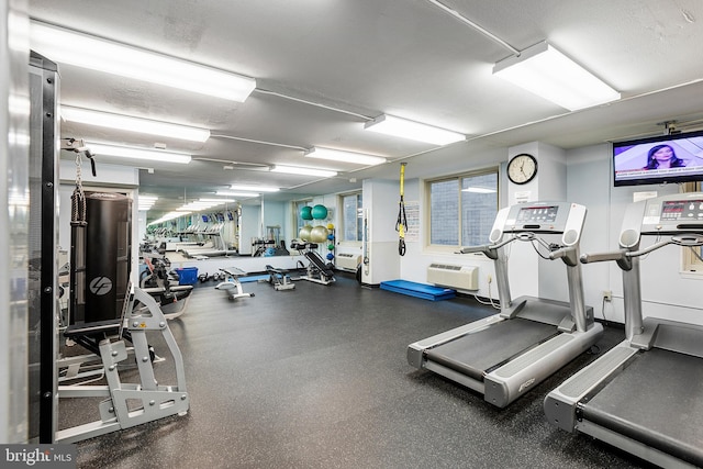 exercise room featuring a wall mounted AC and a textured ceiling