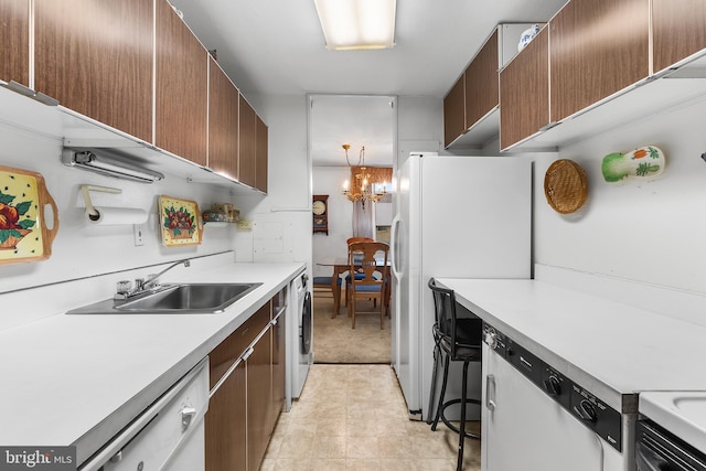 kitchen with light tile patterned floors, white appliances, a notable chandelier, sink, and washer / dryer