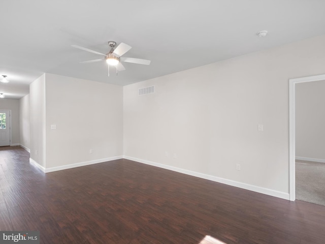 empty room with a ceiling fan, dark wood-style flooring, visible vents, and baseboards