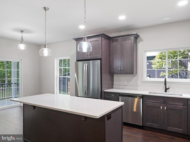 kitchen with stainless steel appliances, a kitchen island, a sink, and light countertops