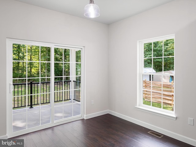 spare room with dark wood-style flooring, visible vents, and baseboards