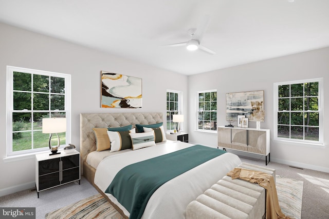 bedroom featuring ceiling fan, multiple windows, baseboards, and light colored carpet