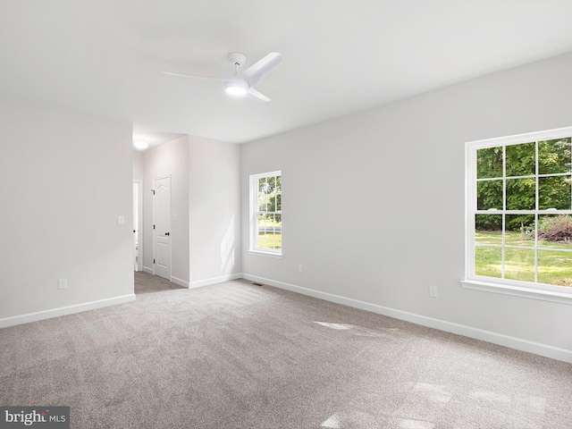 carpeted spare room featuring a ceiling fan, a wealth of natural light, and baseboards