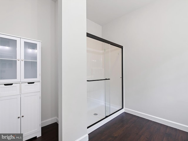 full bath with a stall shower, baseboards, and wood finished floors