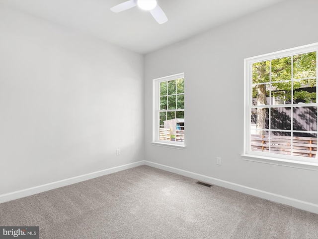 carpeted spare room with a ceiling fan, visible vents, and baseboards