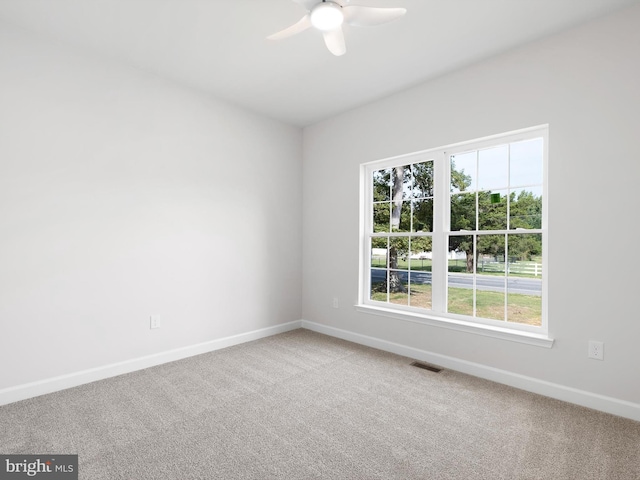 carpeted spare room with a ceiling fan, visible vents, and baseboards