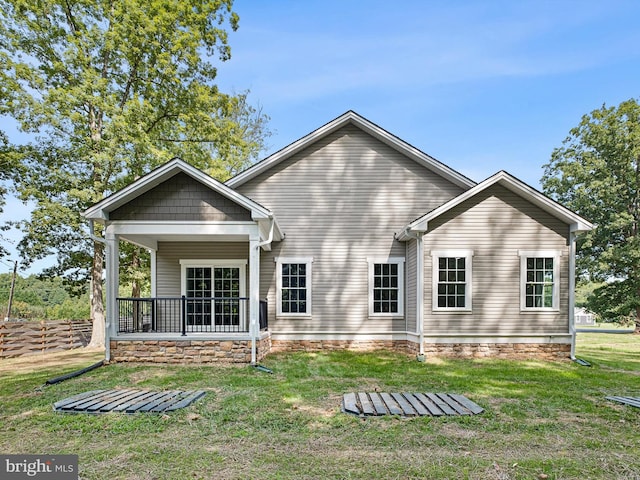 back of house with covered porch and a lawn