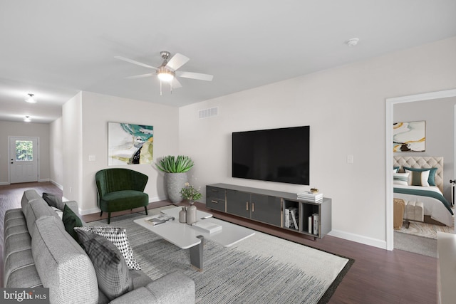 living area with dark wood-type flooring, visible vents, ceiling fan, and baseboards