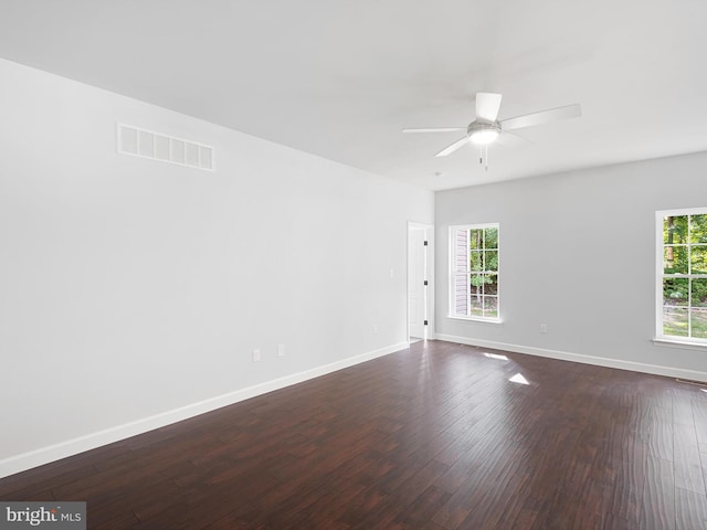 unfurnished room with baseboards, visible vents, dark wood finished floors, and a ceiling fan