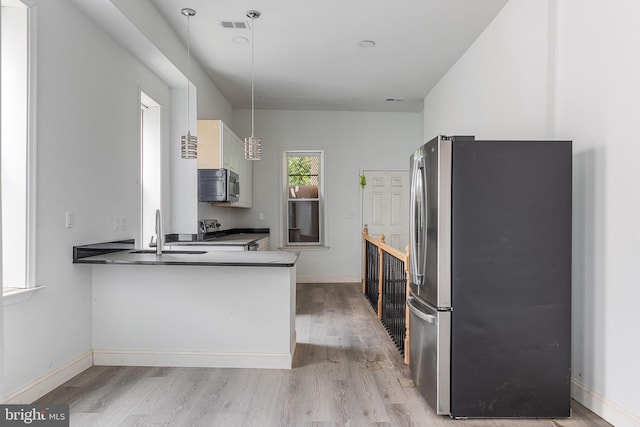 kitchen with light wood finished floors, stainless steel appliances, visible vents, a sink, and baseboards