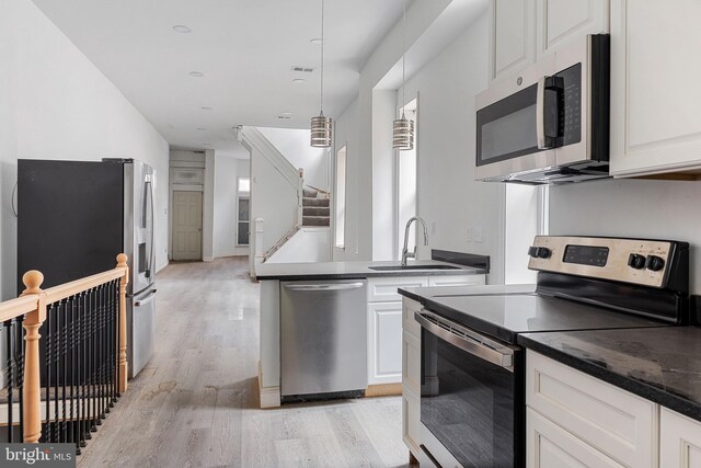 kitchen with light wood-type flooring, white cabinetry, appliances with stainless steel finishes, and a sink