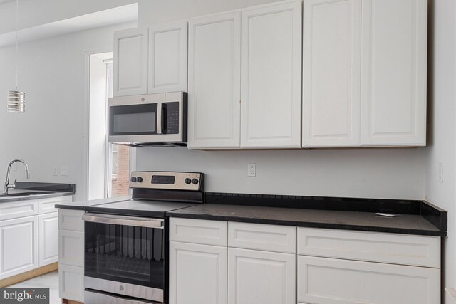 kitchen featuring appliances with stainless steel finishes, dark countertops, and white cabinets