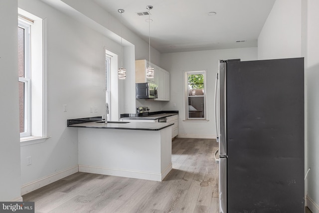 kitchen featuring baseboards, dark countertops, light wood-style flooring, appliances with stainless steel finishes, and a sink