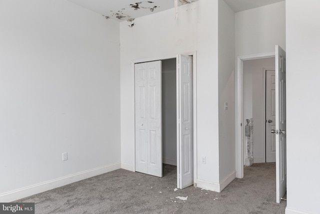 unfurnished bedroom with carpet floors, a closet, and baseboards