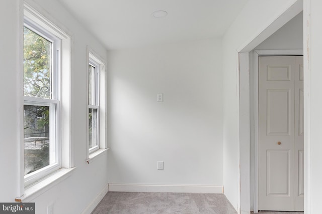 unfurnished room featuring light carpet, baseboards, and a wealth of natural light