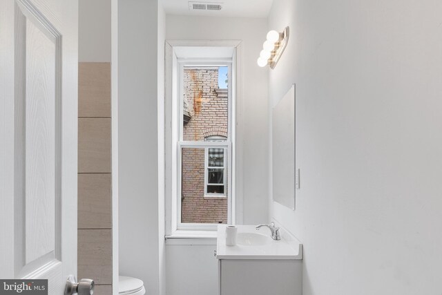 bathroom with toilet, vanity, and visible vents