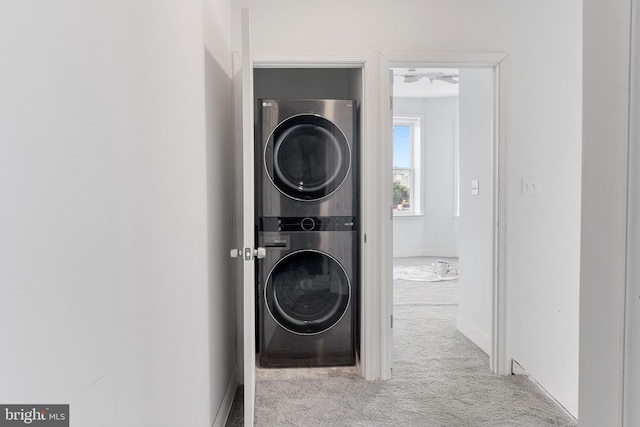 clothes washing area with stacked washer and dryer, carpet floors, and baseboards