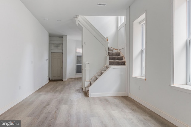 interior space featuring stairway, baseboards, visible vents, and light wood finished floors