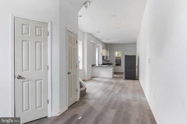 hall featuring light wood-style flooring and baseboards