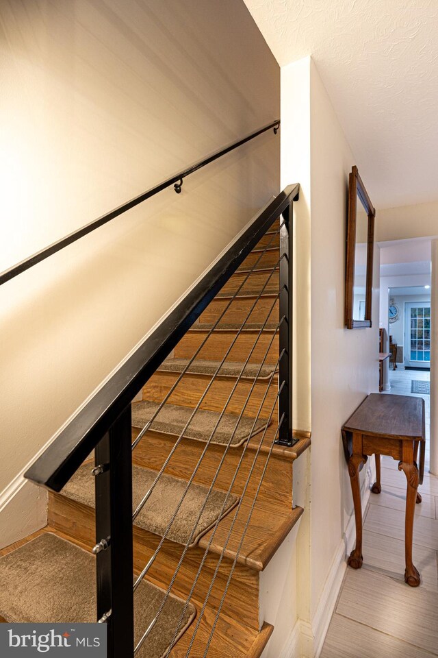 stairway with hardwood / wood-style floors and a textured ceiling