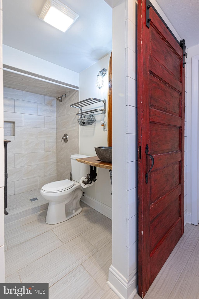 bathroom featuring toilet and a tile shower