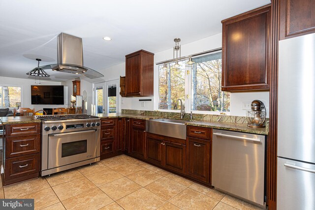 kitchen featuring pendant lighting, sink, appliances with stainless steel finishes, dark stone countertops, and island range hood