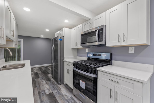 kitchen with stainless steel appliances, light countertops, a sink, and white cabinetry