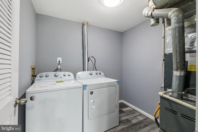 laundry area with washing machine and clothes dryer, dark wood-type flooring, laundry area, and baseboards