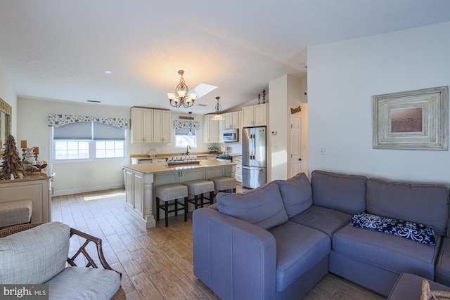 living room with lofted ceiling, light hardwood / wood-style flooring, and a notable chandelier