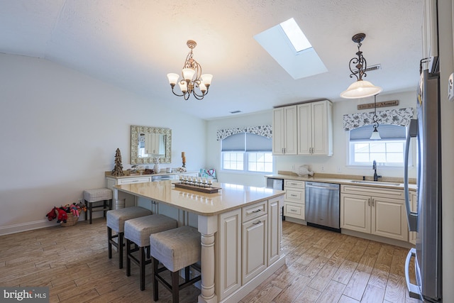 kitchen featuring a healthy amount of sunlight, stainless steel appliances, vaulted ceiling with skylight, and a center island