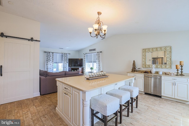 kitchen featuring dishwasher, a barn door, a kitchen island, a kitchen breakfast bar, and light hardwood / wood-style flooring