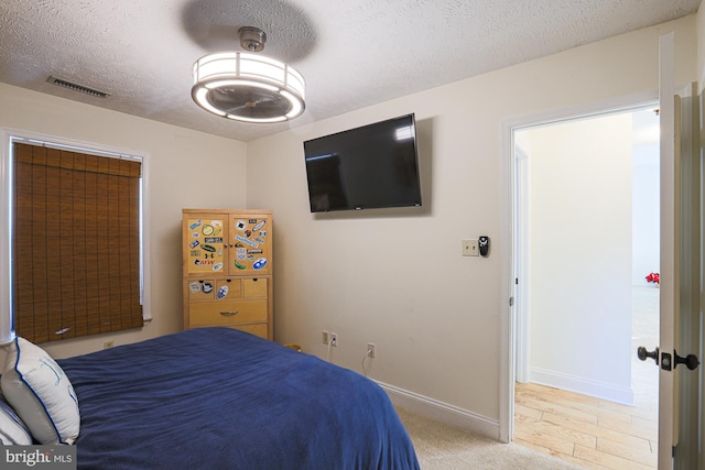 bedroom with a textured ceiling and light hardwood / wood-style flooring