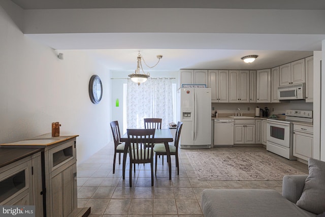 kitchen with an inviting chandelier, light tile patterned flooring, pendant lighting, sink, and white appliances