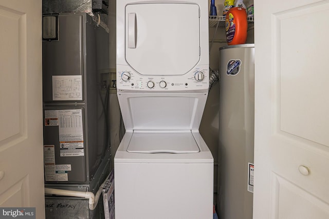 laundry room with water heater and stacked washer / dryer