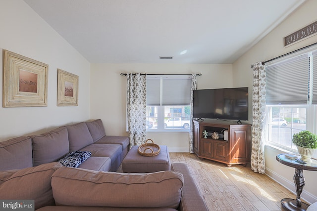 living room featuring a healthy amount of sunlight, vaulted ceiling, and light hardwood / wood-style floors