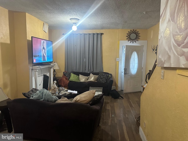 living room featuring a textured ceiling, a large fireplace, and dark hardwood / wood-style floors