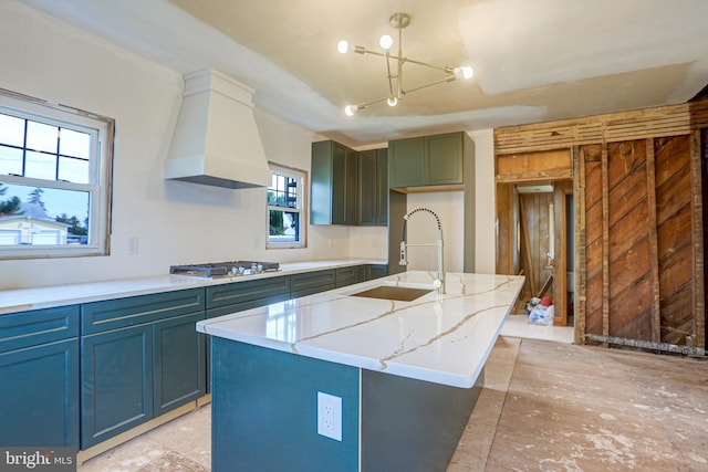 kitchen with a healthy amount of sunlight, an island with sink, custom range hood, and sink